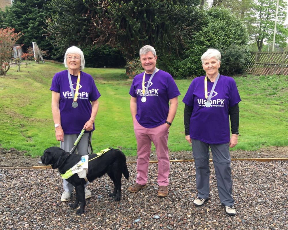3 kiltwalkers and a guide dogs posing with their medals