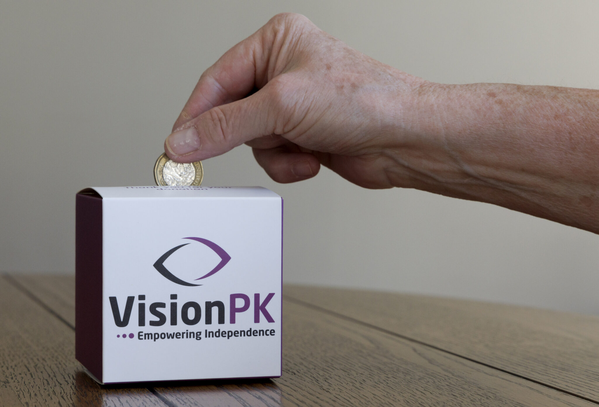 VisionPK money box with a hand placing a coin into it