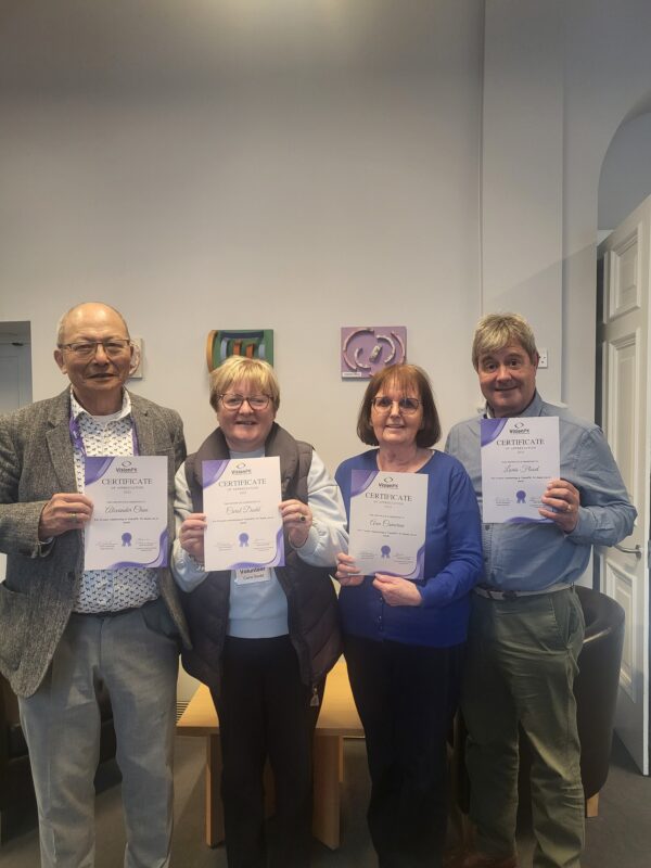 4 people holding volunteering certificates smiling at the camera